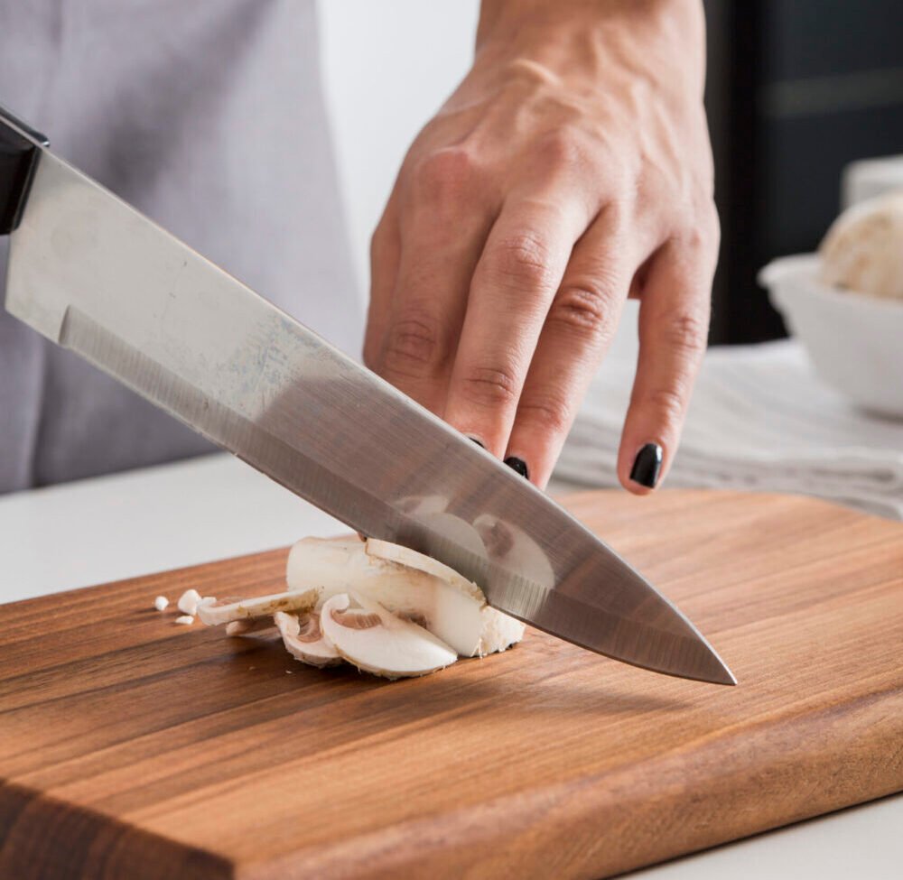 close-up-woman-s-hand-cutting-mushroom-with-knife-chopping-board