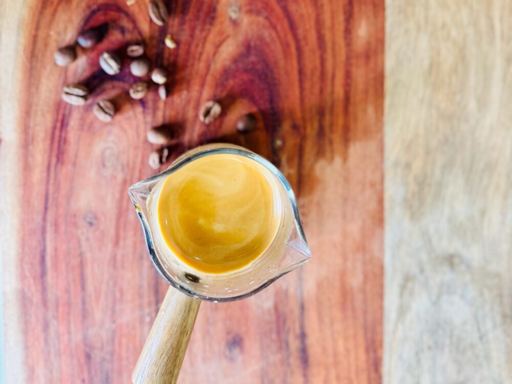 overhead shot of espresso shot on cutting board with coffee beans