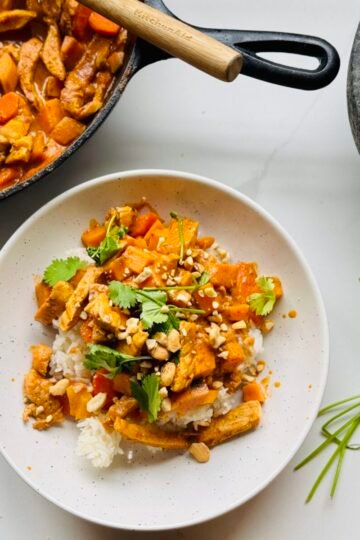 panang curry served over rice overshot with crushed peanuts cilantro and curry in pan