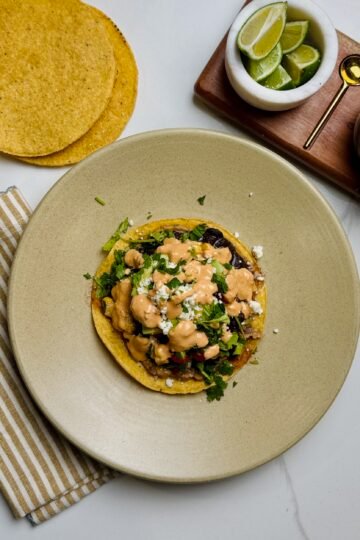 Veggie tostadas on a plate with lime and queso fresco cheese