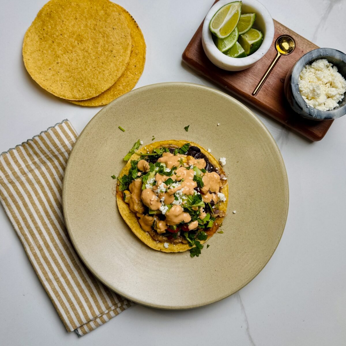 Veggie tostadas on a plate with lime and queso fresco cheese