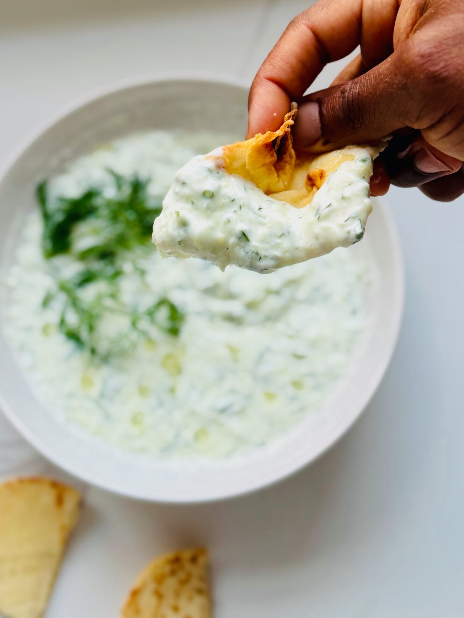 Creamy homemade tzatziki sauce scooped on pita bread 
