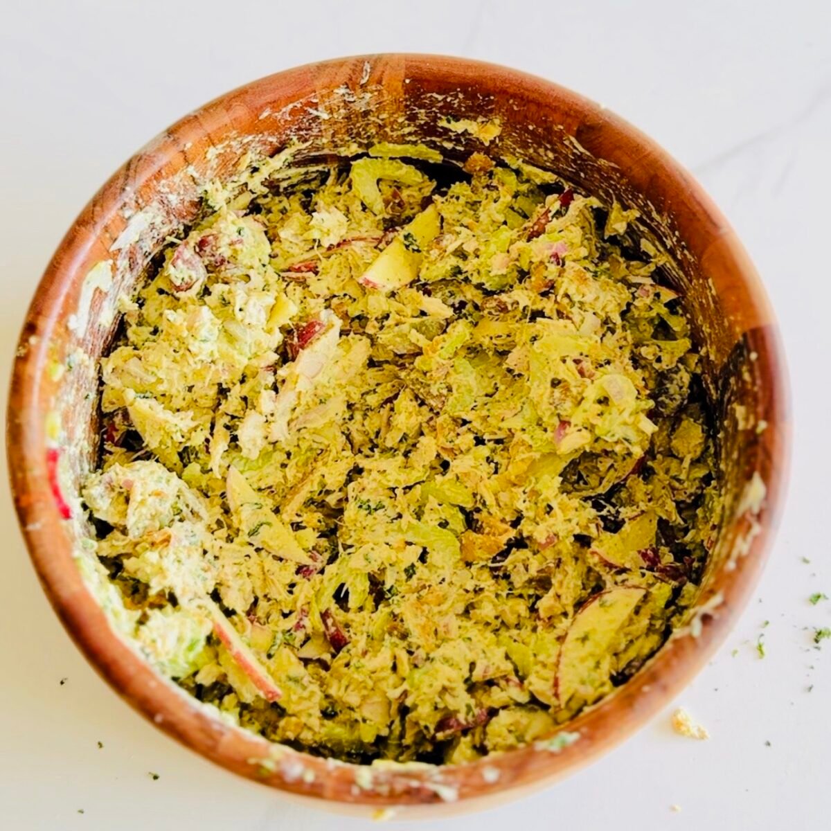 Rotisserie chicken salad with grapes apples pistachios and green sauce in a serving bowl