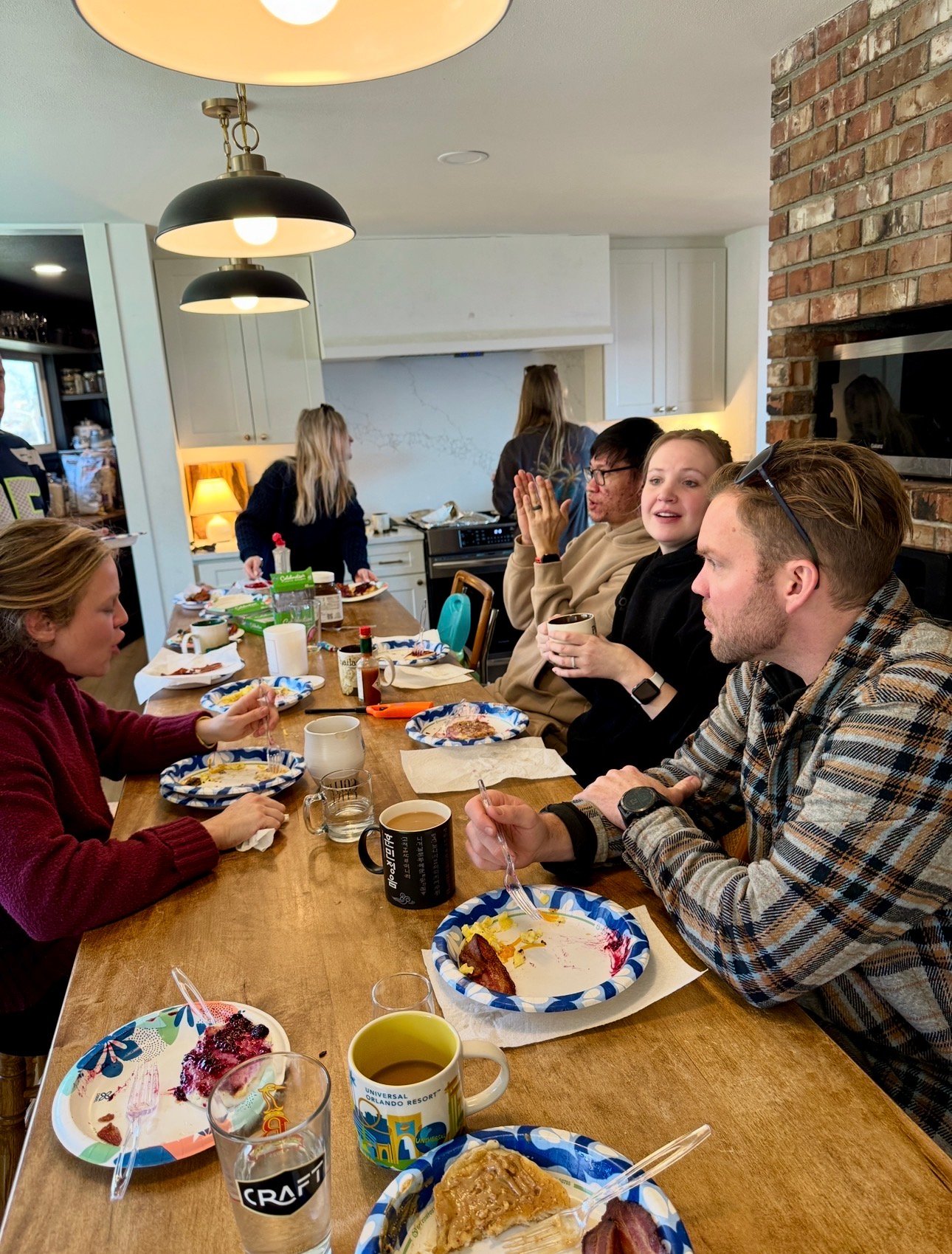 people gathered around a table eating and talking how to host at home