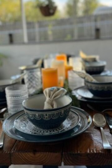 Table set with plates, bowls and candles in the middle showing how to host at home