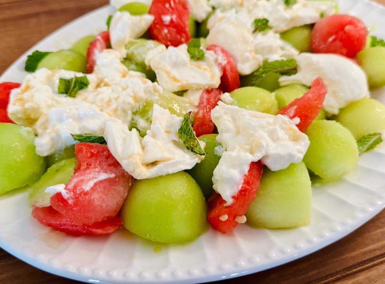 Melon burrata mint salad served on a white platter for a spring dinner party