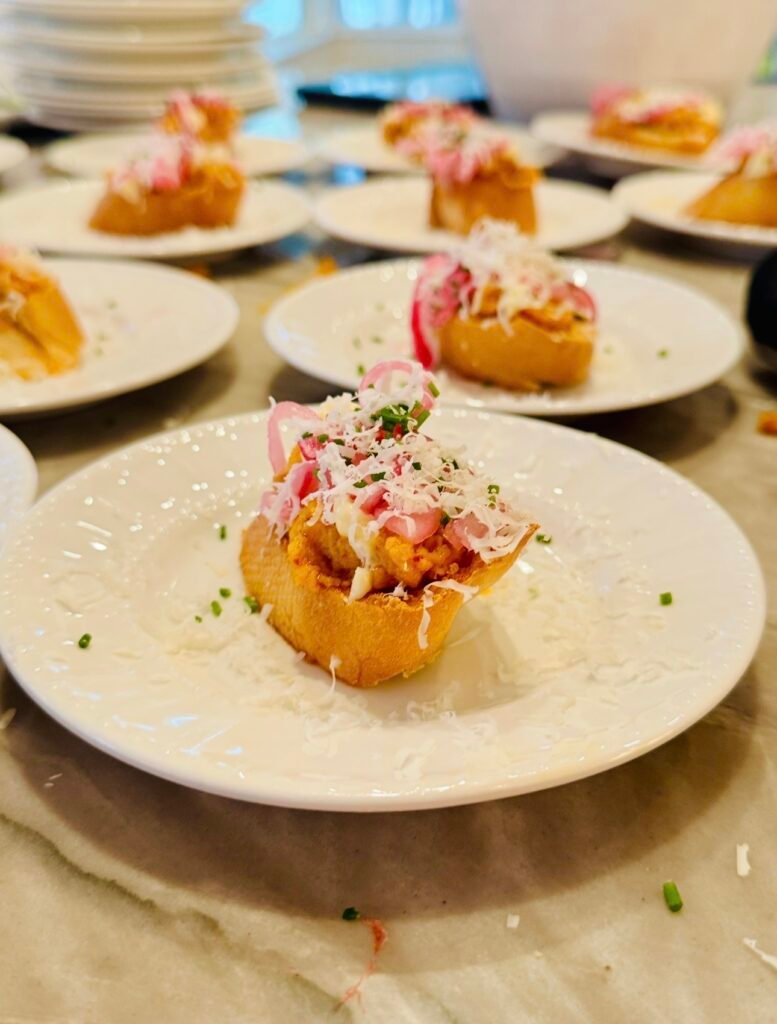 Deviled egg toast topped with pickled red onion and chives on toasted baguette