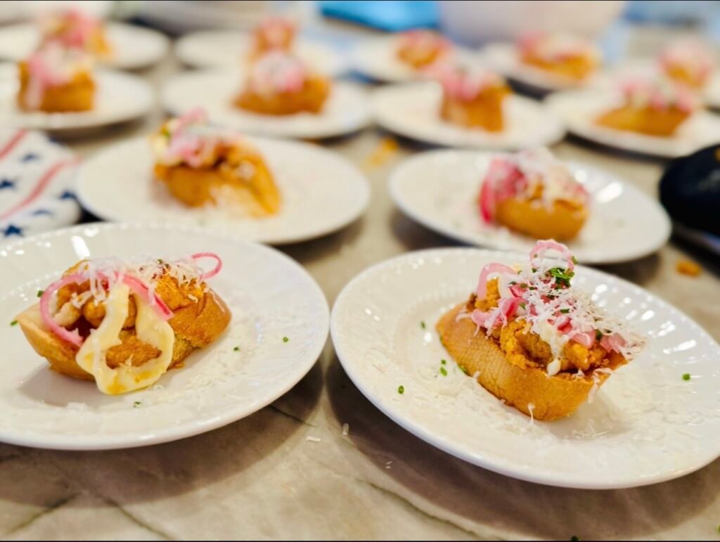 Deviled egg toast topped with pickled red onion and chives on toasted baguette