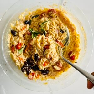 Roasted feta with cherry tomatoes, Kalamata olives, garlic, olive oil, and spices in a glass baking dish