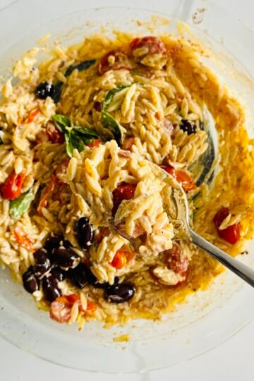 Roasted feta with cherry tomatoes, Kalamata olives, garlic, olive oil, and spices in a glass baking dish