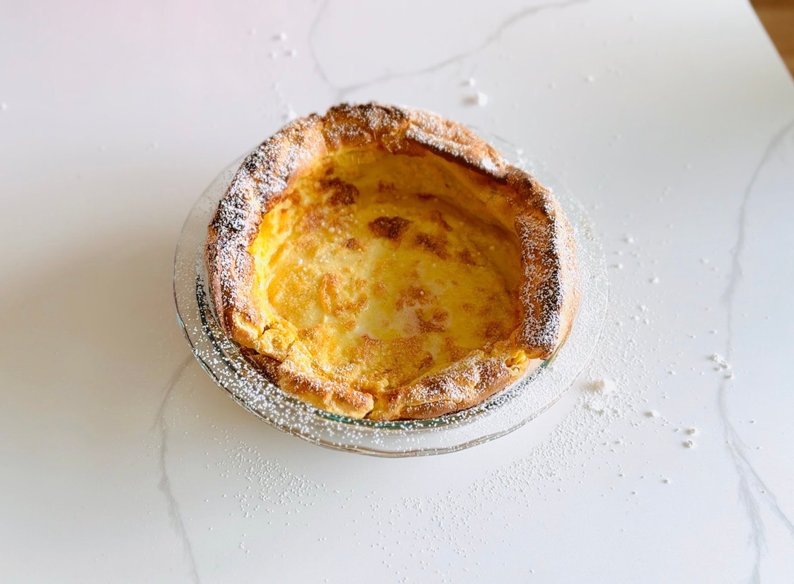  Easy German pancakes puffed and golden in a baking dish with powdered sugar 