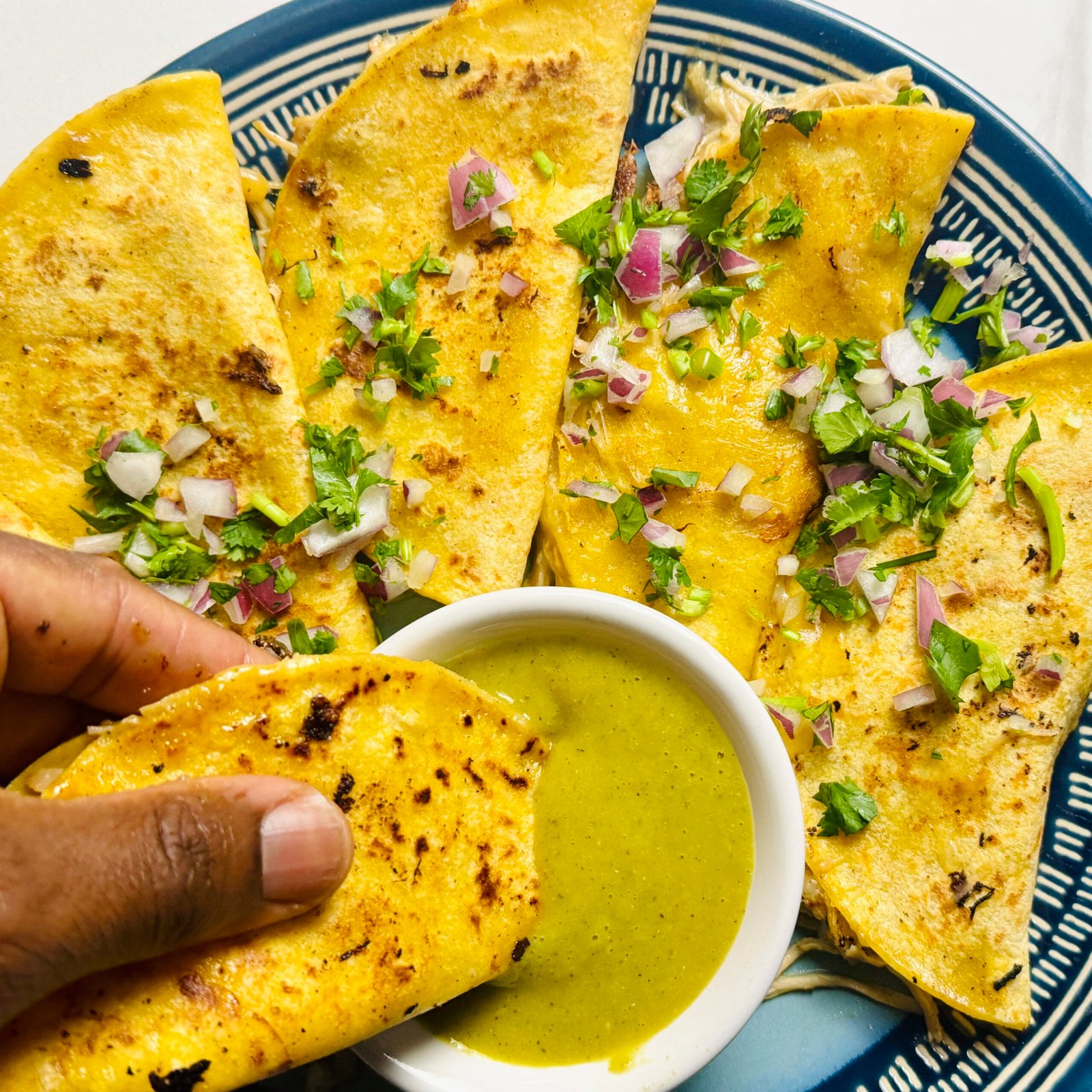 Crispy mojo chicken taco being dipped into homemade charred tomatillo salsa verde