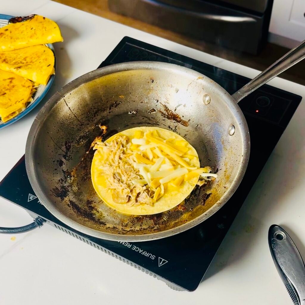 Corn tortilla tacos filled with mojo chicken and cheese crisping in a skillet