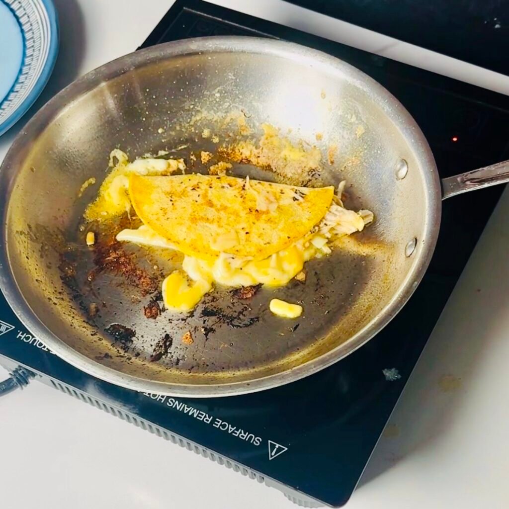 Corn tortilla tacos filled with mojo chicken and cheese crisping in a skillet