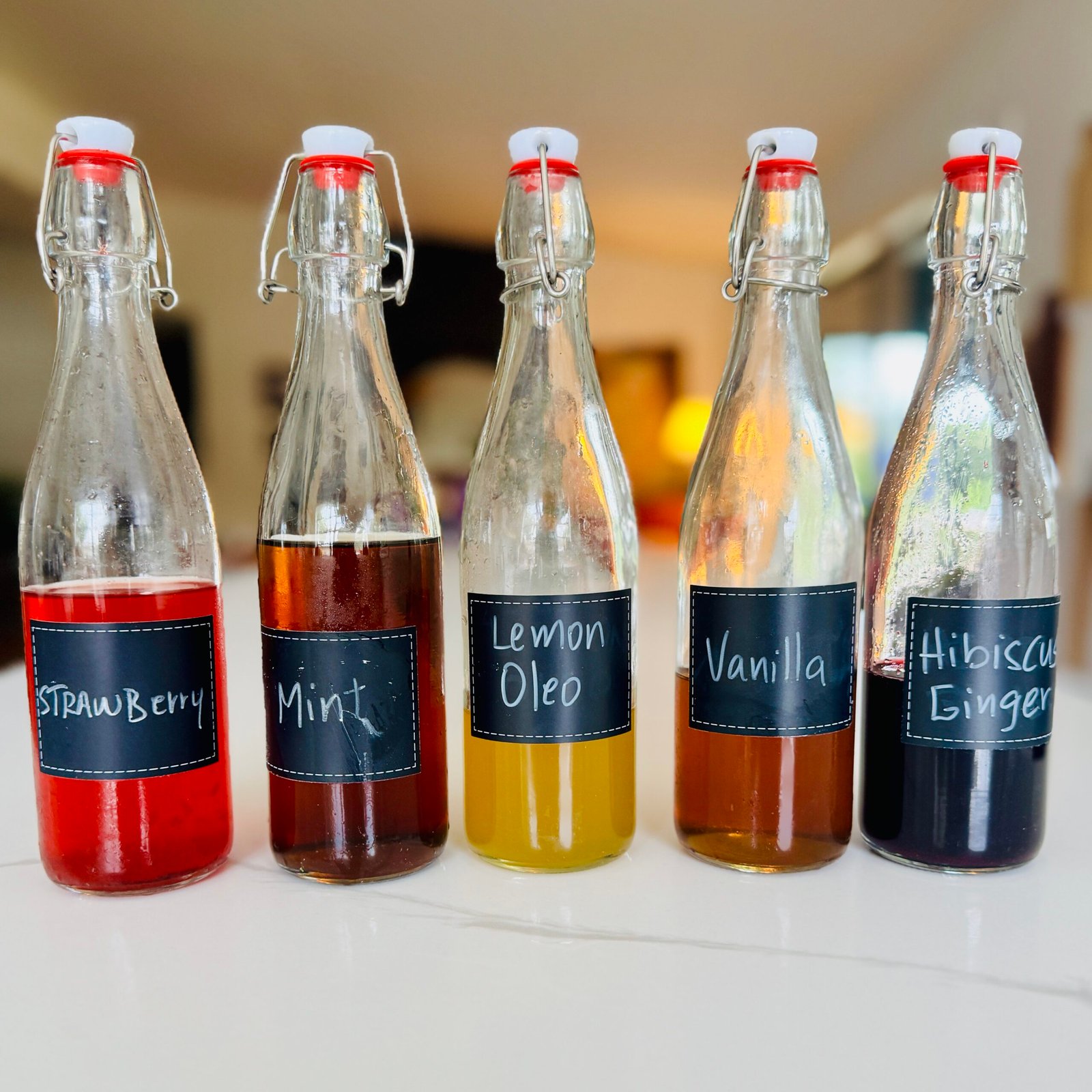 Homemade flavored syrups for drinks made with mint strawberries lemon vanilla hibiscus and ginger