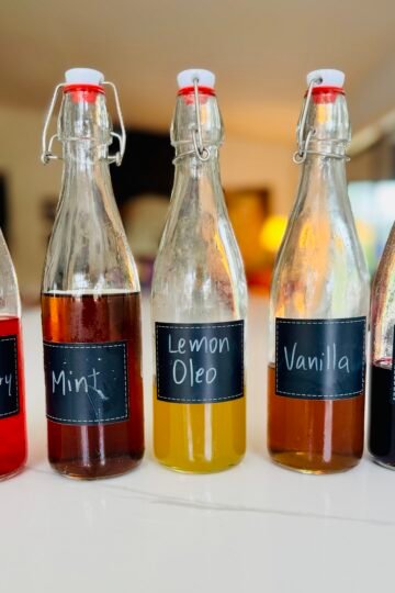 Five homemade flavored syrups for drinks made with mint, strawberries, lemon, vanilla, hibiscus, and ginger
