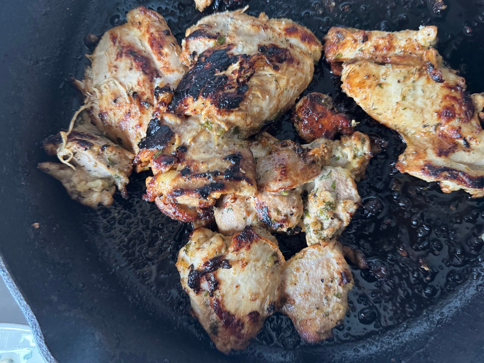 Greek yogurt marinated chicken thighs browned in a cast iron skillet