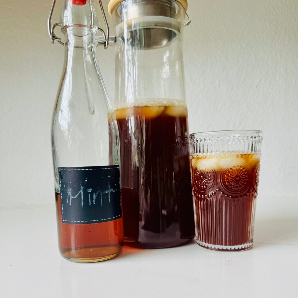 Five drinks made with mint simple syrup including lemonade, iced tea, a sparkler, a gin smash, and a mojito