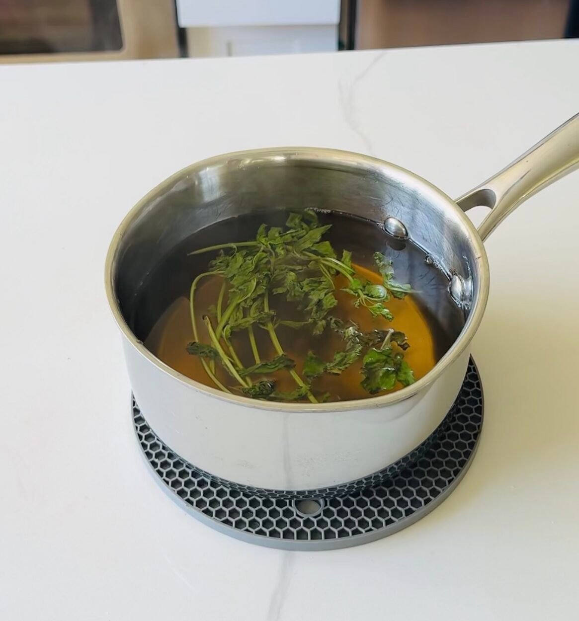 Fresh mint steeping off heat in homemade simple syrup before straining