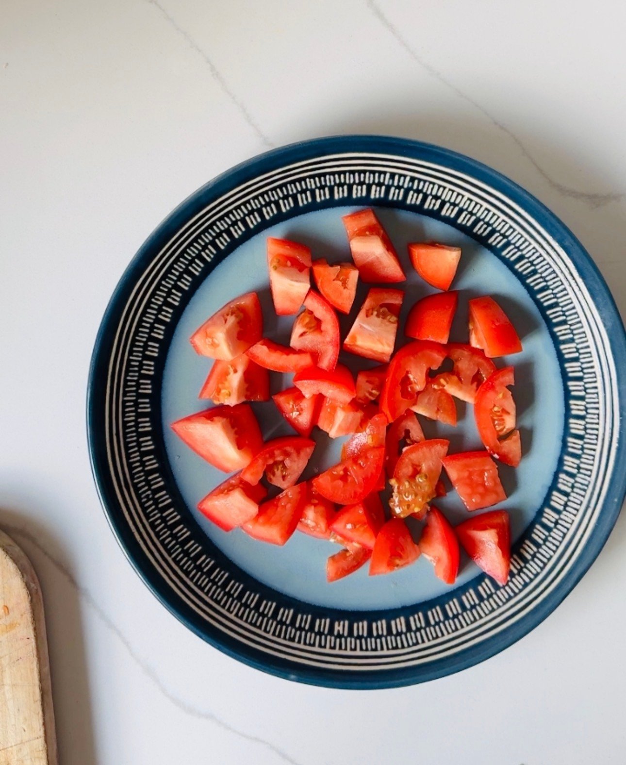 Chopped tomatoes forming the first layer of cucumber tomato avocado feta salad.