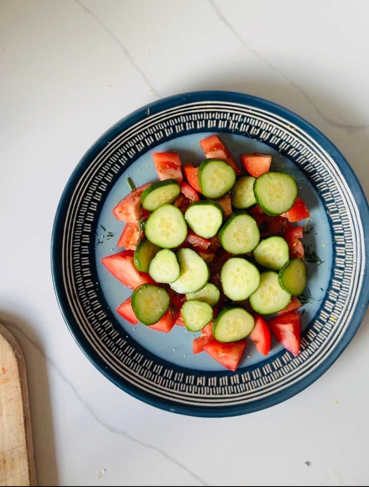 Sliced cucumber layered over seasoned tomatoes with fresh dill.