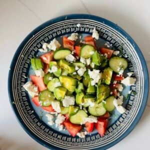 Finished cucumber tomato avocado feta salad with fresh dill and crumbled feta.