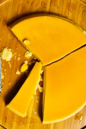 Overhead view of extra creamy caramel flan with vanilla bean specks and a slice removed.