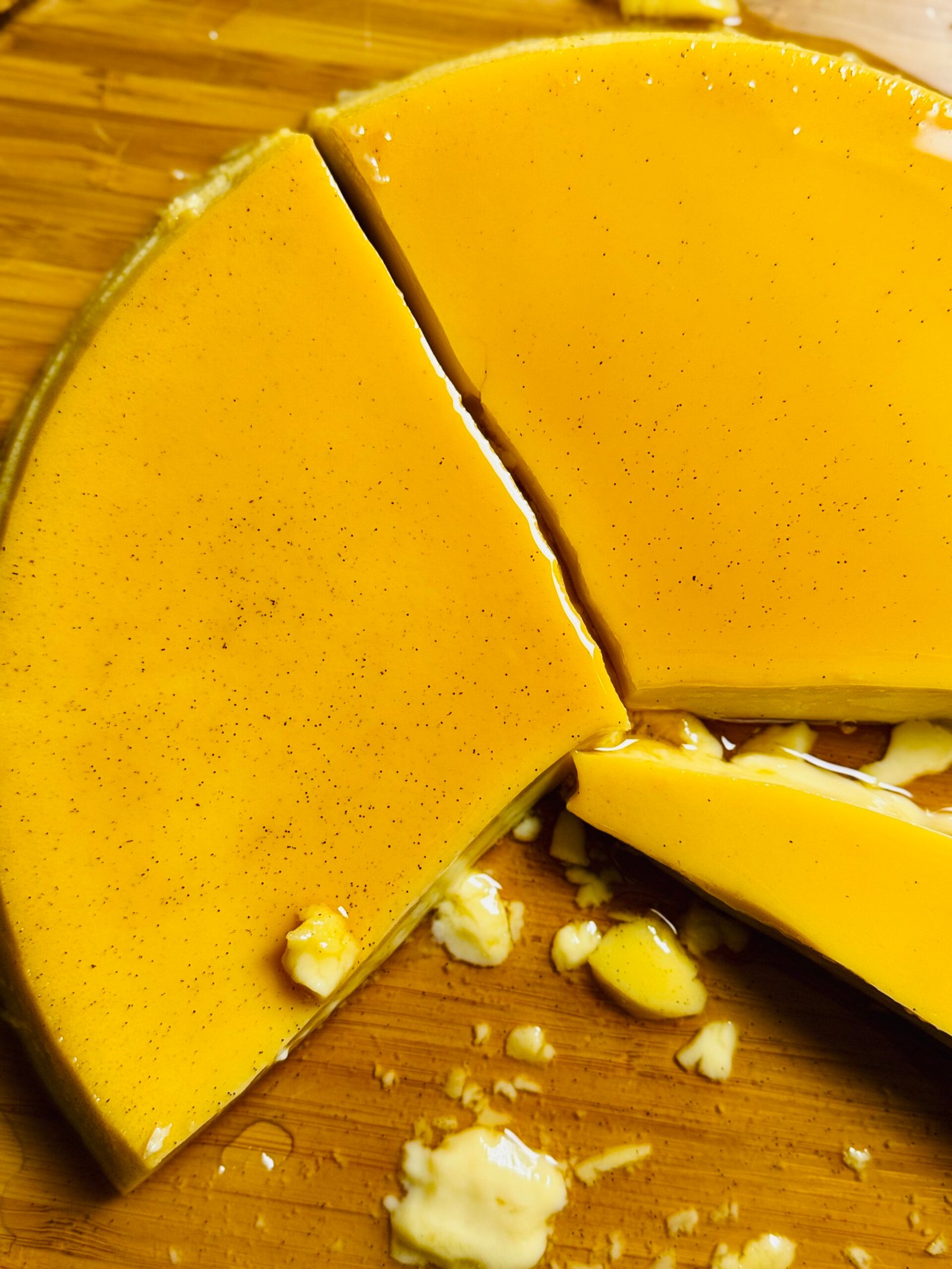 Close-up of caramel flan showing vanilla bean specks and a smooth custard texture.