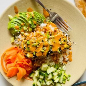 Close view of soy ginger glazed skillet salmon over rice with fresh vegetables and creamy gochujang sauce