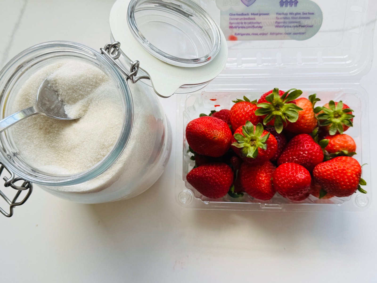 Fresh strawberries and granulated sugar for making cold strawberry syrup.