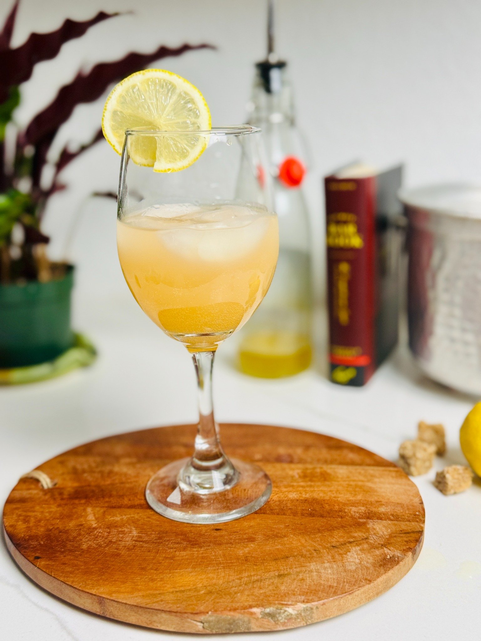 Grapefruit-lemon oleo ginger spritz in a stemmed glass with ice and a lemon wheel.
