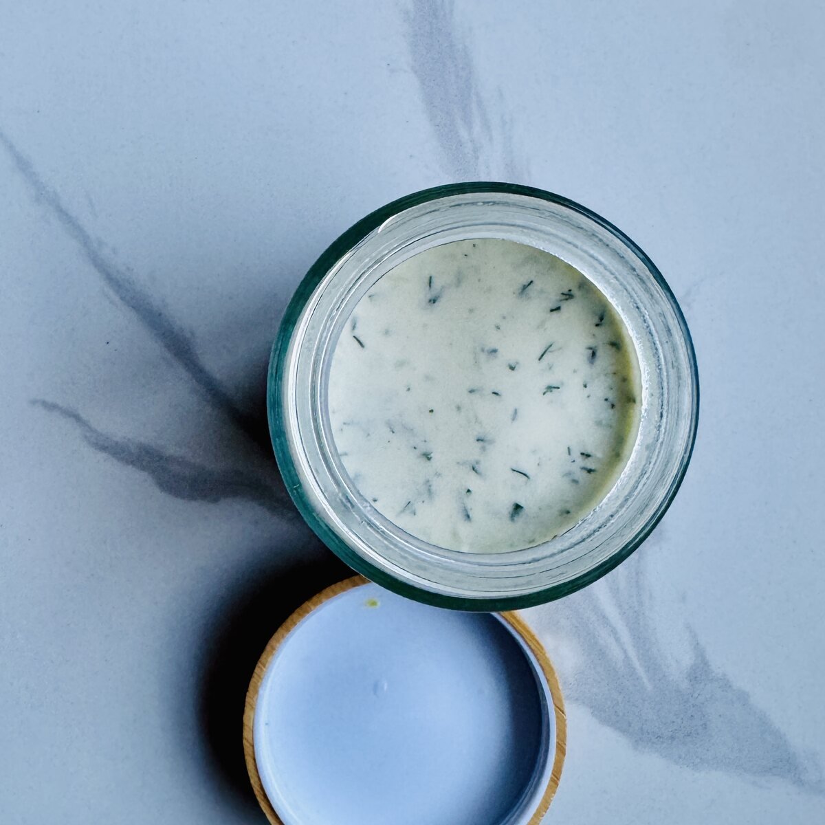 Greek yogurt chicken marinade with lemon, garlic, oregano, cumin, and olive oil in a glass jar