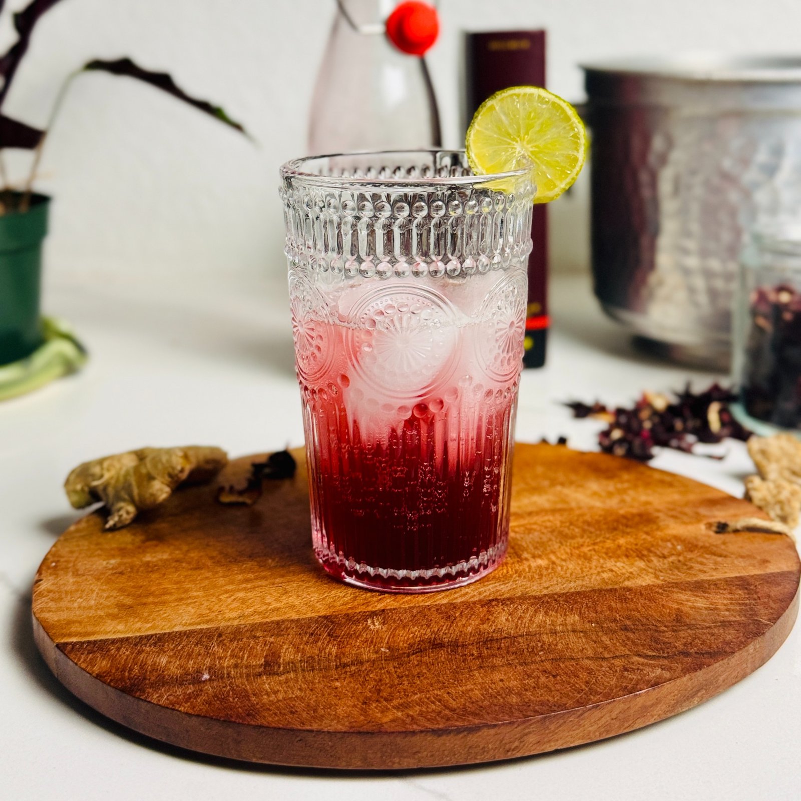 Hibiscus-ginger lime soda with a deep red syrup layer, ice, and a lime wheel.