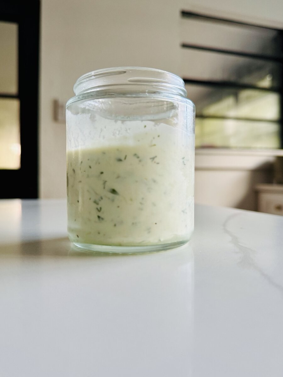 Homemade Greek yogurt chicken marinade with herbs in a glass jar on a kitchen counter