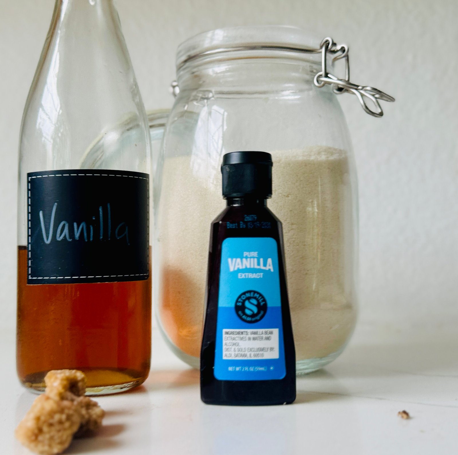 Homemade vanilla syrup in a labeled glass bottle beside granulated sugar and vanilla extract.