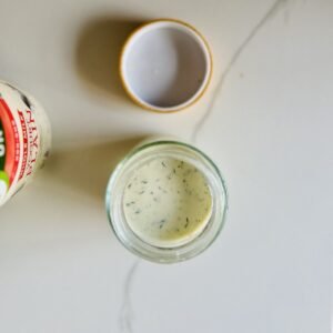 Overhead view of Greek yogurt chicken marinade beside plain Greek yogurt on a light counter