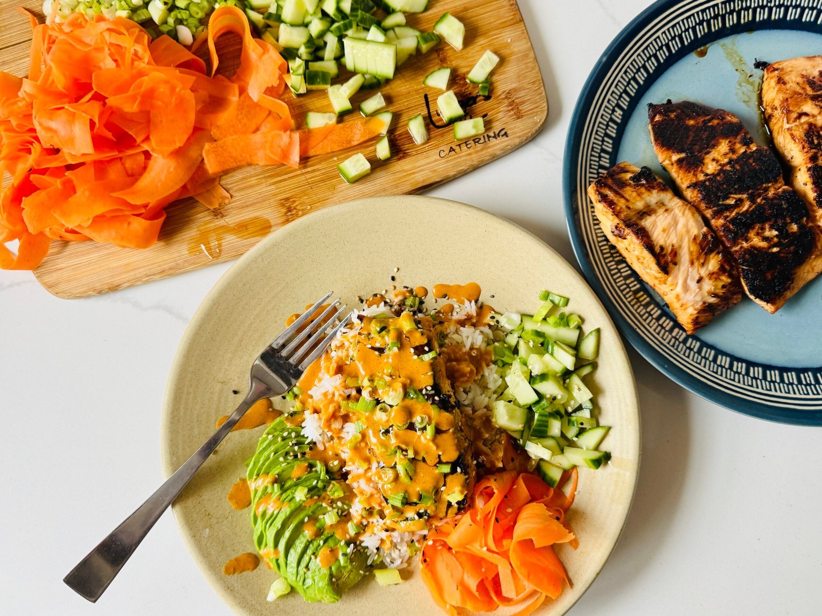 Skillet-seared soy ginger salmon fillet served over jasmine rice with cucumber, carrots, avocado, and sesame seeds
