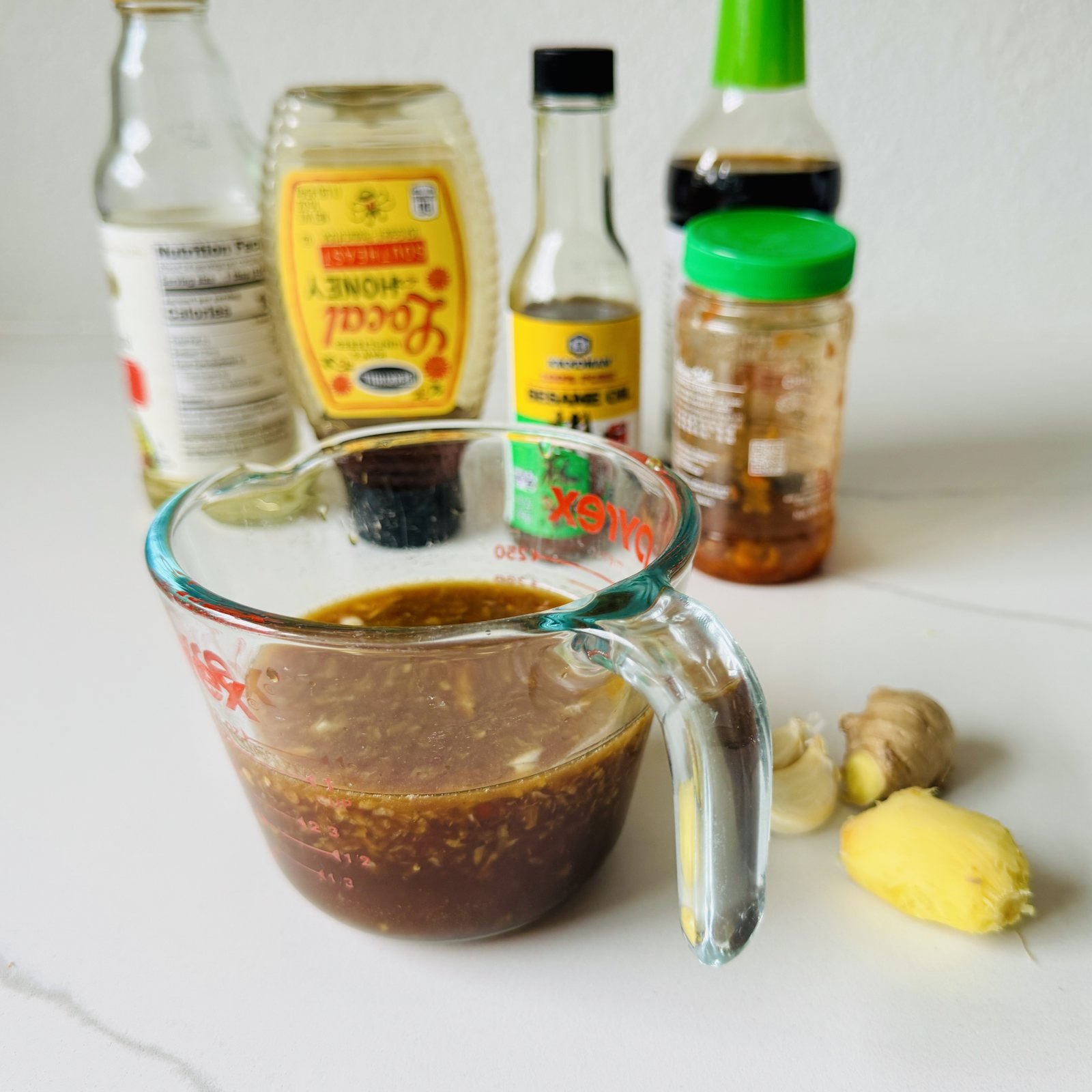 Soy ginger marinade in a glass measuring cup with honey, rice vinegar, soy sauce, sesame oil, fresh ginger, and garlic