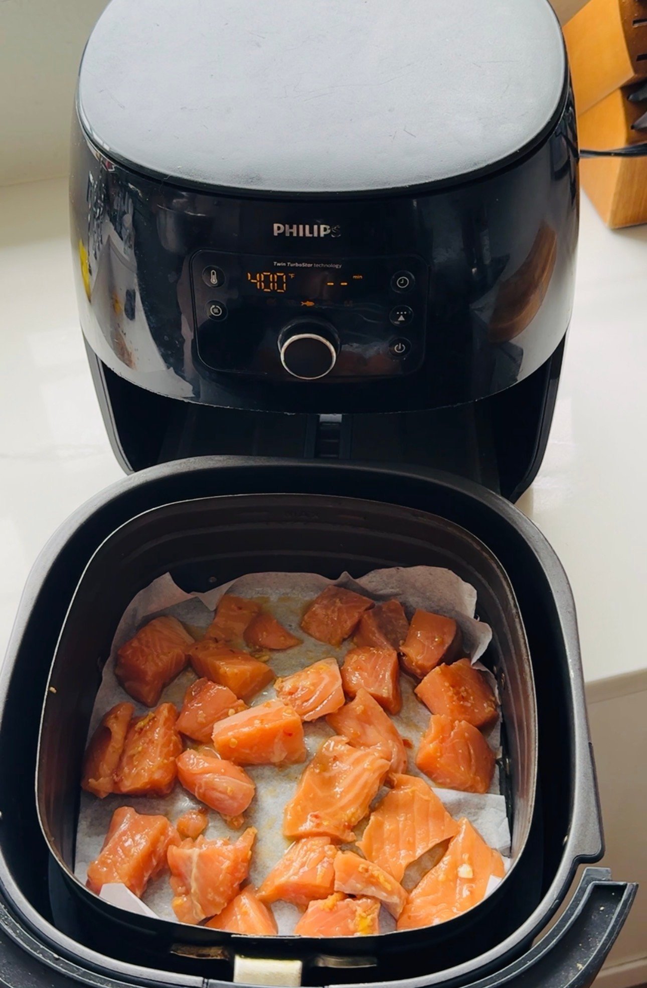 Soy ginger salmon bites cooking in a single layer in an air fryer basket at 400 degrees