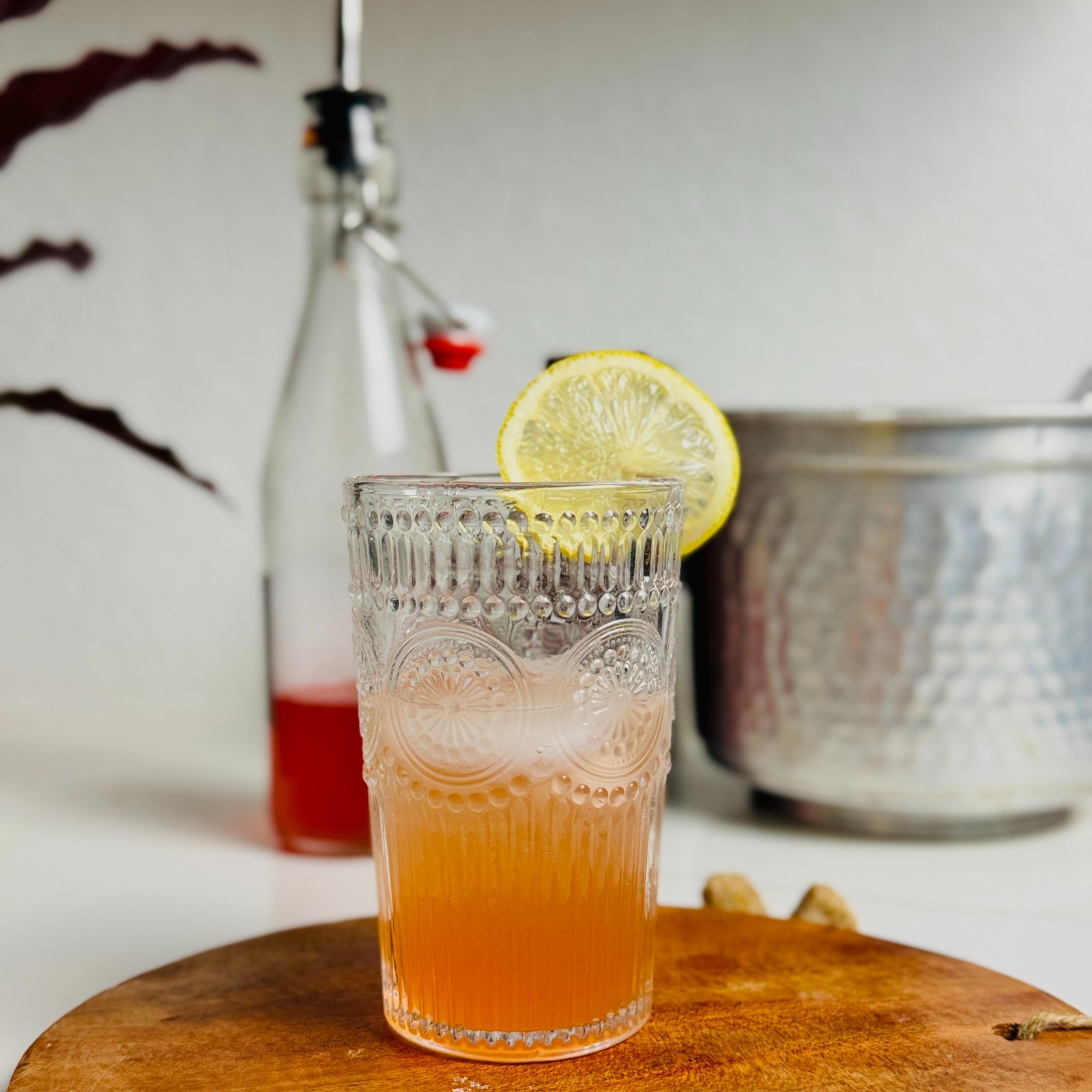 Sparkling strawberry lemonade over ice in a tall glass with a lemon wheel.