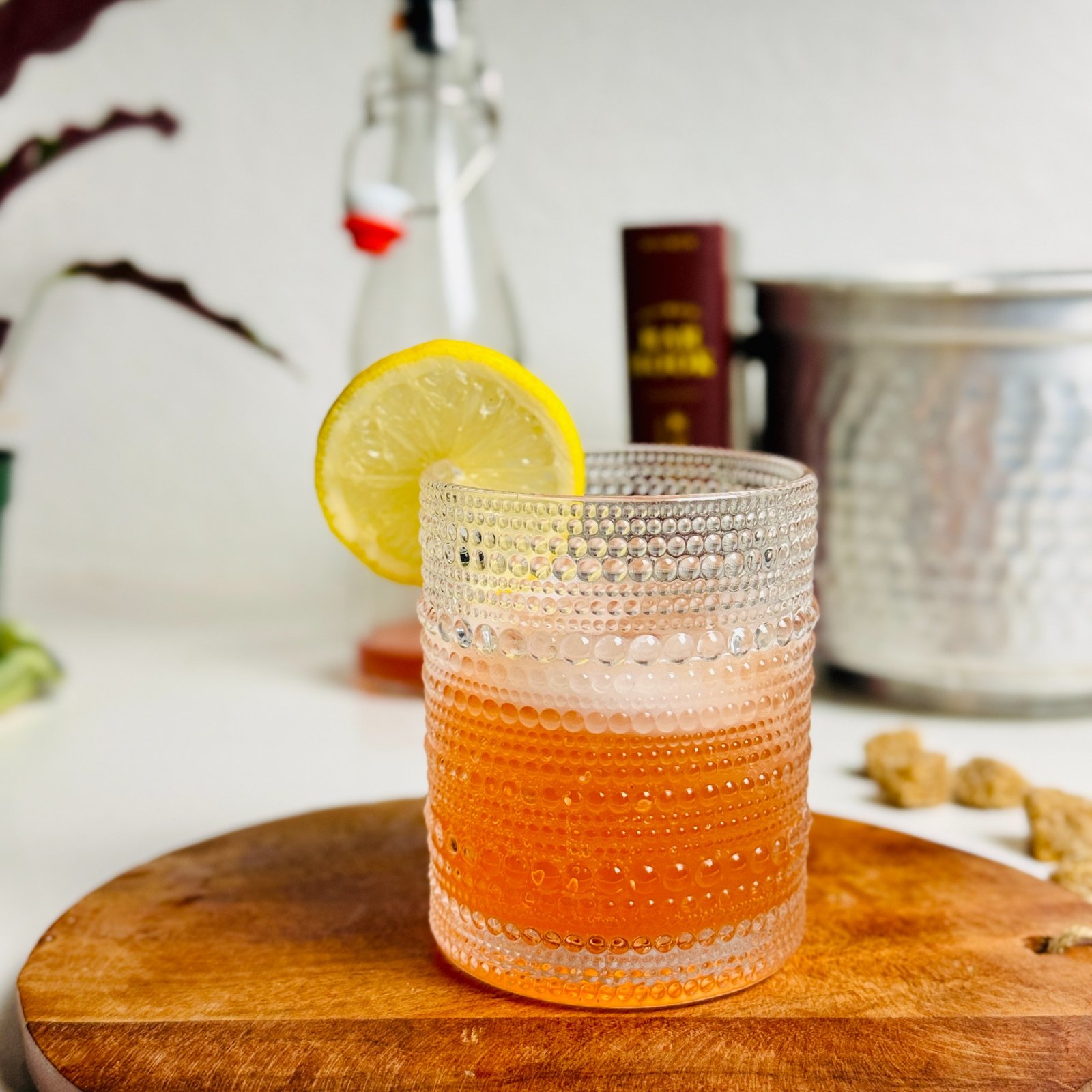 Strawberry gin Collins over ice in a textured glass with a lemon wheel.