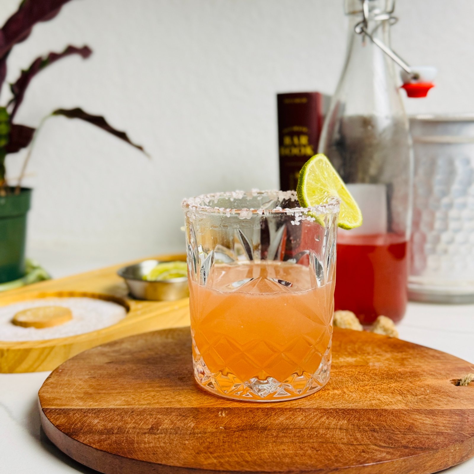 Strawberry margarita over ice in a salt-rimmed rocks glass with a lime wheel.