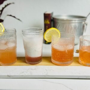 Four strawberry syrup drinks: lemonade, Italian cream soda, gin Collins, and a salt-rimmed margarita.