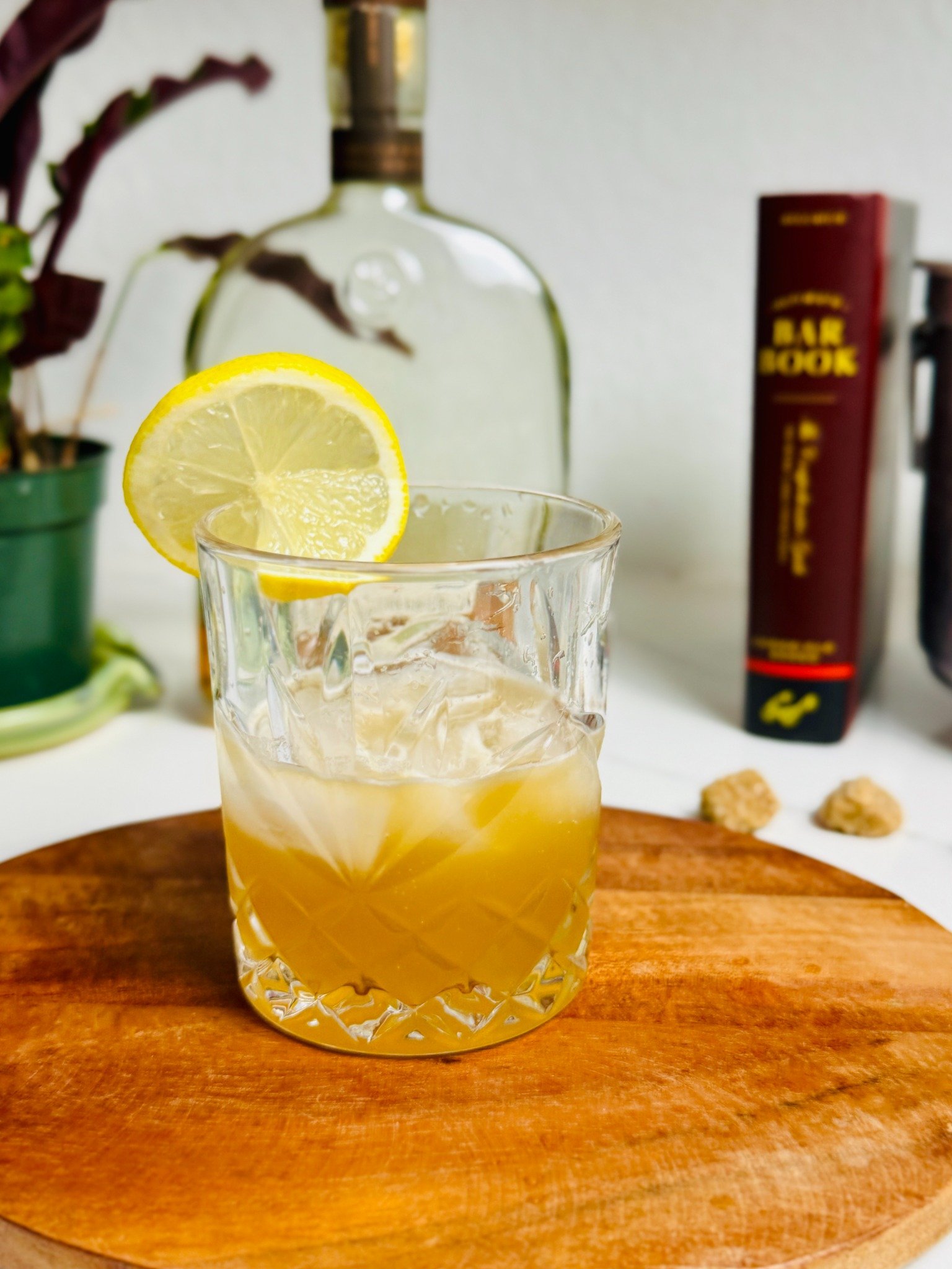 Amber vanilla bourbon sour over ice with a lemon wheel on a wooden board.