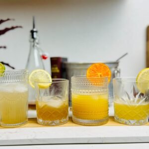 Vanilla syrup drinks with citrus garnishes arranged beside a bottle of homemade syrup.