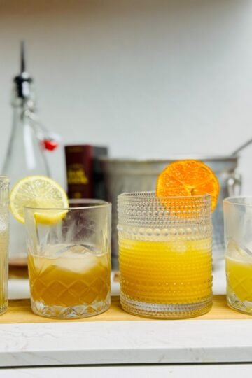 Vanilla syrup drinks with citrus garnishes arranged beside a bottle of homemade syrup.