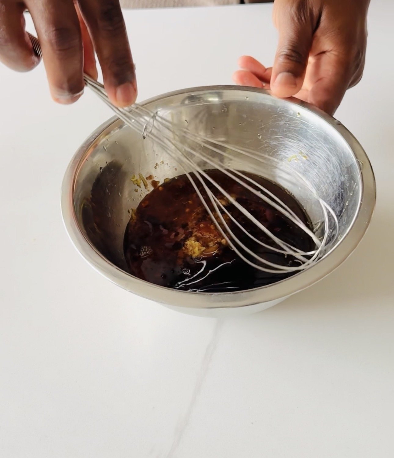 Soy ginger marinade being whisked with honey, rice vinegar, fresh ginger, garlic, sesame oil, and sriracha