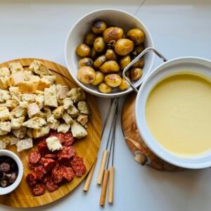 Gruyère and Gouda fondue served with a variety of foods arranged for dipping.