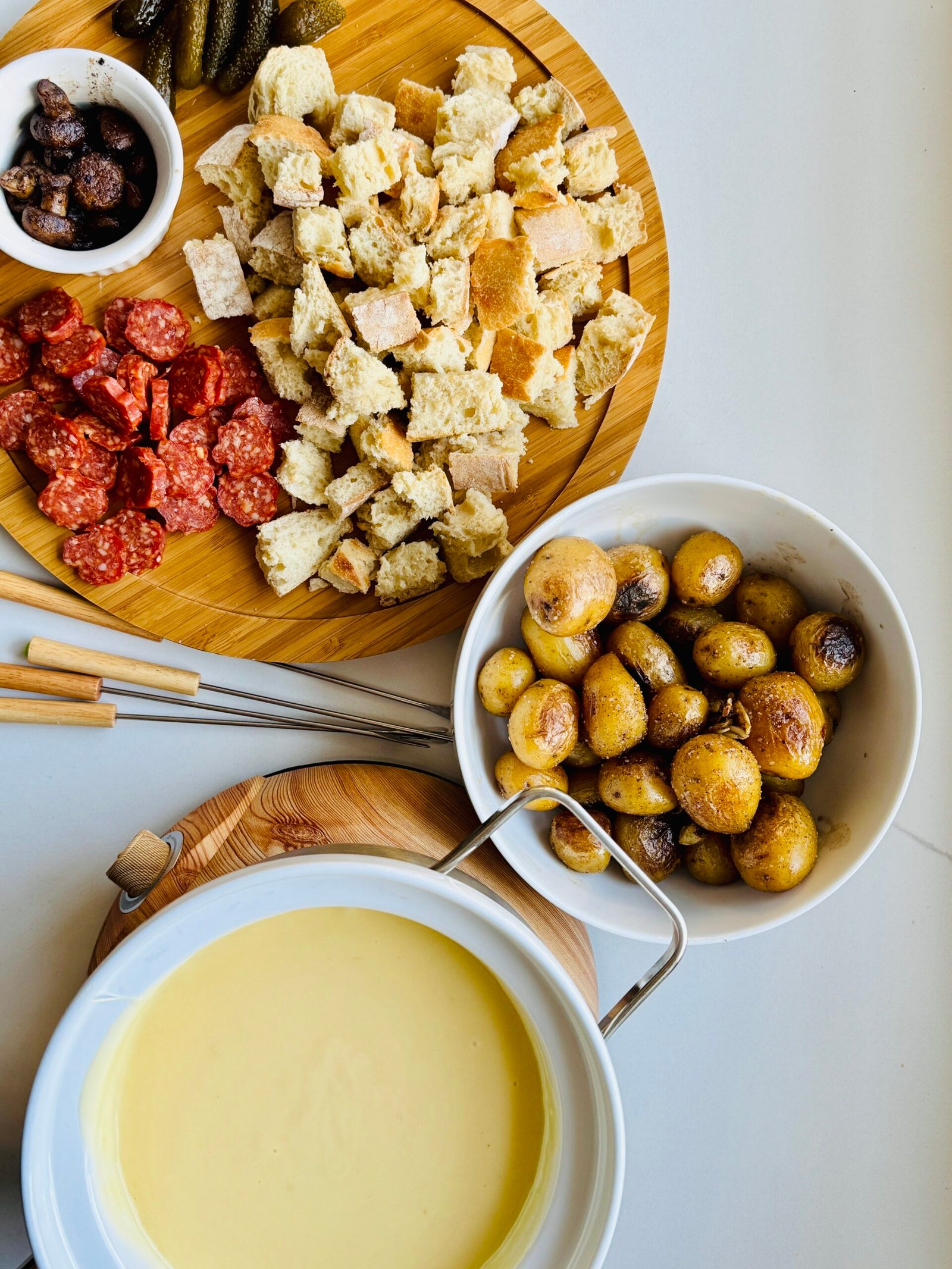 Gruyère and Gouda cheese fondue set out with bread and other foods for dipping.
