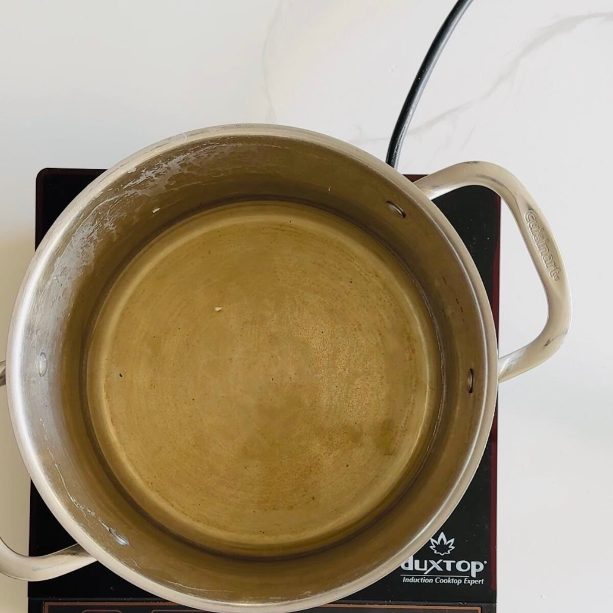 White wine warming in a pot during the first stage of making cheese fondue.